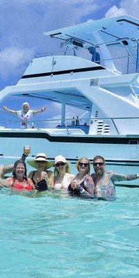 Group of friends swimming beside a yacht in Punta Cana