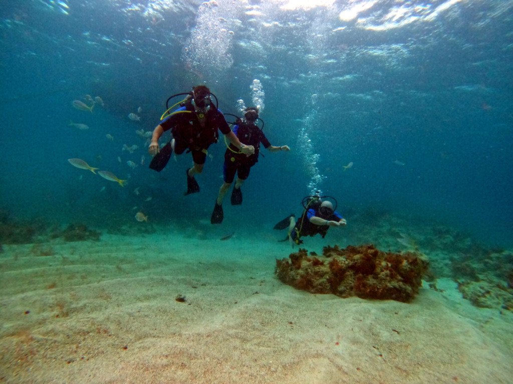 Buceador haciendo la señal de OK bajo el agua durante una sesión de descubre el buceo